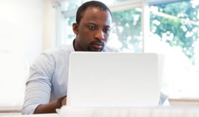 Man sits in front of white laptop.
