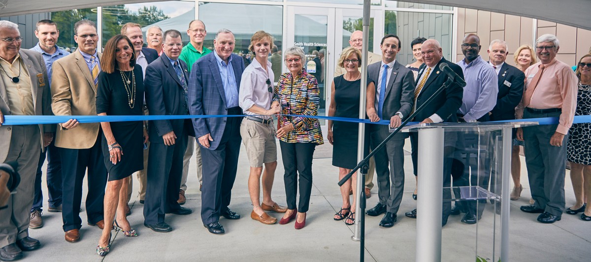 Large group of DCCC leaders pose ready to cut ribbon of new building.