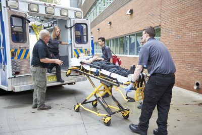 EMS student placing stretcher in ambulance.