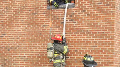 Firefighter repelling down brick building