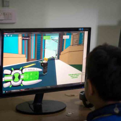 Student in front of computer screen with animated game on it
