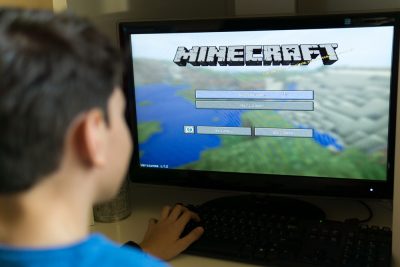 Student in front of computer screen with Minecraft game on screen