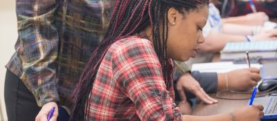 Student at desk uses pen to write