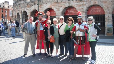 Travelers posed with costumed Roman Legions in front of roman architecture
