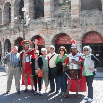 Travelers posed with costumed Roman Legions in front of roman architecture