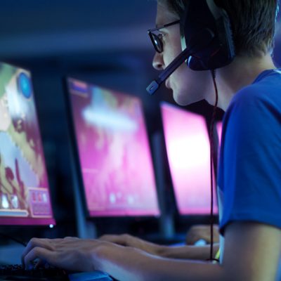 Individual with gaming headset in front of computer screen in dark room