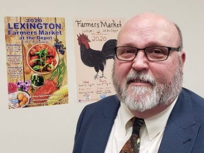 DCCC student John Pettit stands next to his Farmers Market poster.