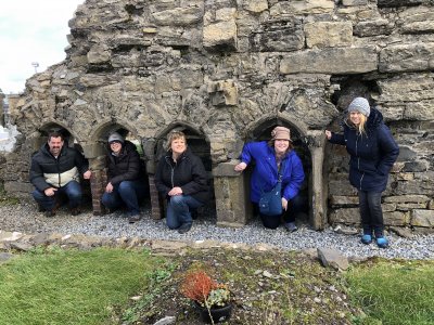 5 travelers dressed in warm clothes nestled under ancient architectural structure