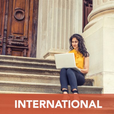 Female sitting on steps of ornate building working on laptop. Text reads: "International"