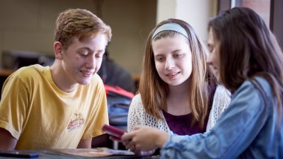 Three young students looking at a digital device