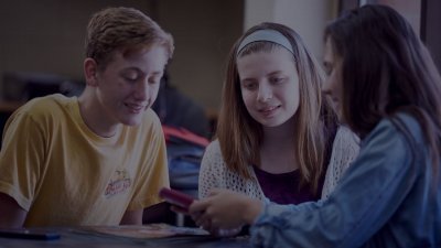 Three young students looking at a digital device