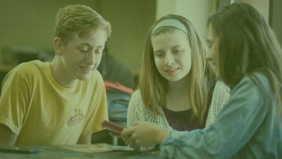 Three young students looking at a digital device