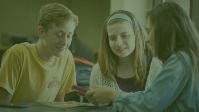 Three young students looking at a digital device