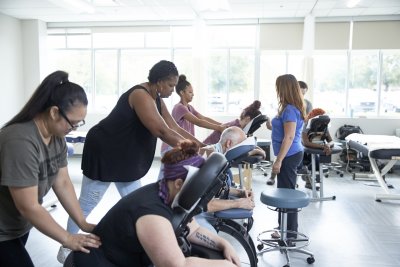 Multiple students giving massages with instructor watching