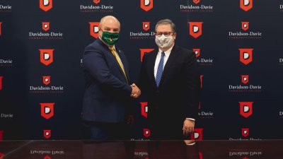 Dr. Hartness & Lees Mcrae representative shaking hands in front of backdrop