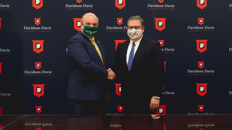 Dr. Hartness & Lees Mcrae representative shaking hands in front of backdrop