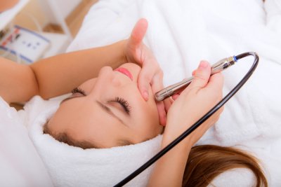 Esthetics technician's hand using instrument on patient's face