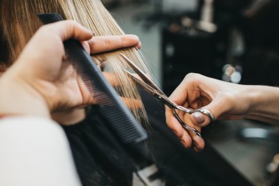 hands with scissors and comb styling someones hair