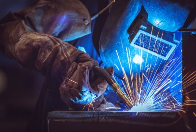 Welder in blue mask and gloves with sparks flying