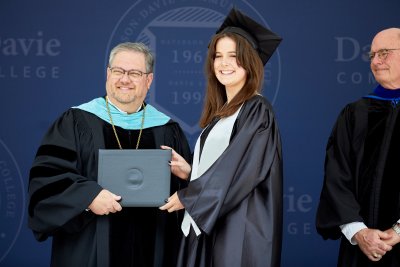 Dr. Darrin Hartness posing for photo with graduate holding a diploma