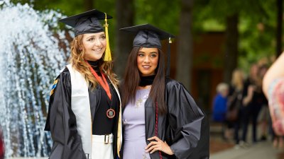 Two graduates in cap and gown in courtyard