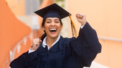 Graduate in cap and gown cheers in excitement