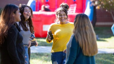 Four students happily talking in front of outdoor inflatable