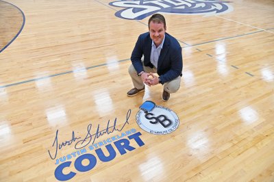 Justin Strickland kneeling beside his name on Brinkley Gym floor