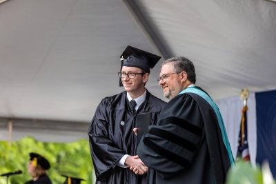 Graduate shakes Dr. Hartness' hand as they receive their diploma