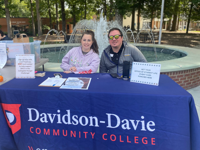 Student Life representatives sitting behind table with blue Davidson-Davie tablecloth on it