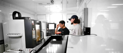 Two students in safety glasses look at Computer Integrated Machining device