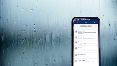 Phone with StormTrac dashboard on screen in front of window pane with rain on it