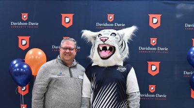 Darrin Hartness poses for photo with Davidson-Davie mascot, Stormy