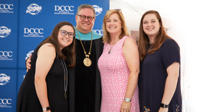 Dr. Darrin Hartness and family posing in from of blue backdrop.
