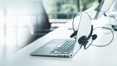 Laptop with headset sitting on top of white desk.