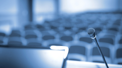 Empty podium with microphone overlooks empty room of chairs.