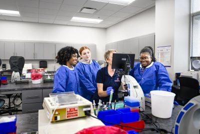 Medical Laboratory Technology Students With Instructor at microscope.