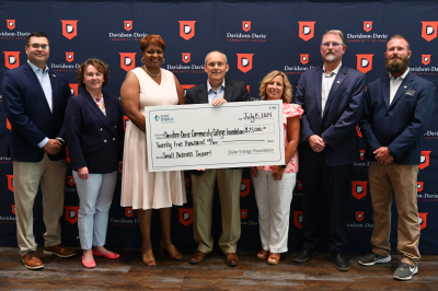 Representatives from Davidson-Davie Community College, Thomasville and Duke Energy pose in front of Davidson-Davie backdrop with large check for 25,000