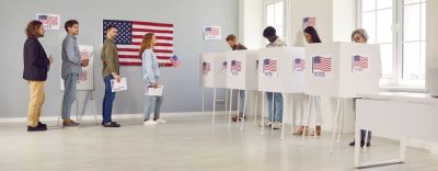 a line of people waiting in line to vote at a polling location with american flag on wall