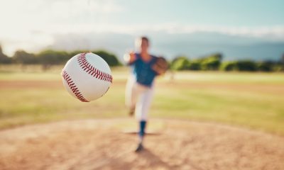 Baseball in the foreground with a blurred out baseball player in the background.