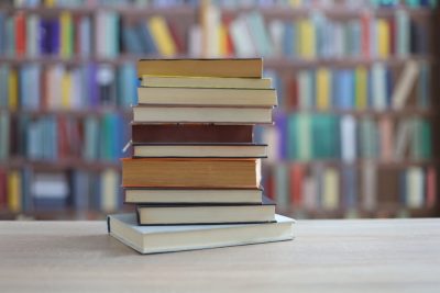 stack of books on wooden table in library