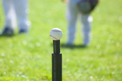 White baseball sitting on top of a black batting tee..