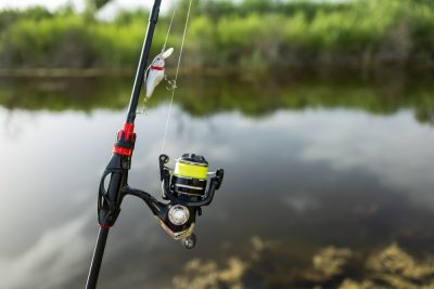 Close-up of fishing rod reels. Fishing on the shore of the lake. Spinning rods for sport fishing.