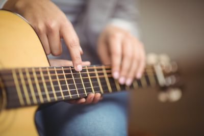 Close of of someone instructing another person where to place hands on a guitar