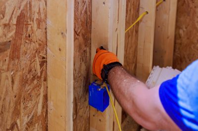 Electrician installs electrical wires on site during construction of residential building