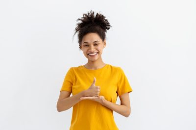 young girl in yellow shirt doing sign language