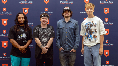 Four young men standing in front of a "Davidson-Davie Community College" backdrop.