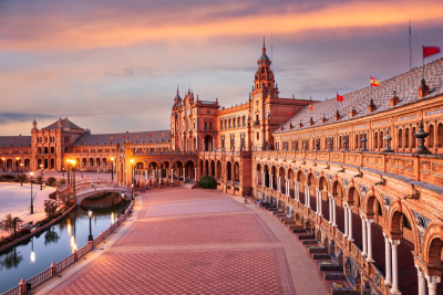 Plaza de España in Seville, Spain, at sunset, showcasing its semi-circular architectural design and canal.
